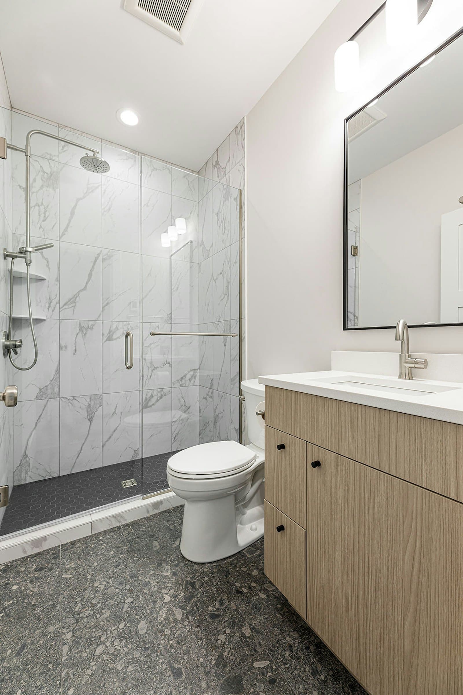 Bathroom with glass shower, toilet, and wood vanity