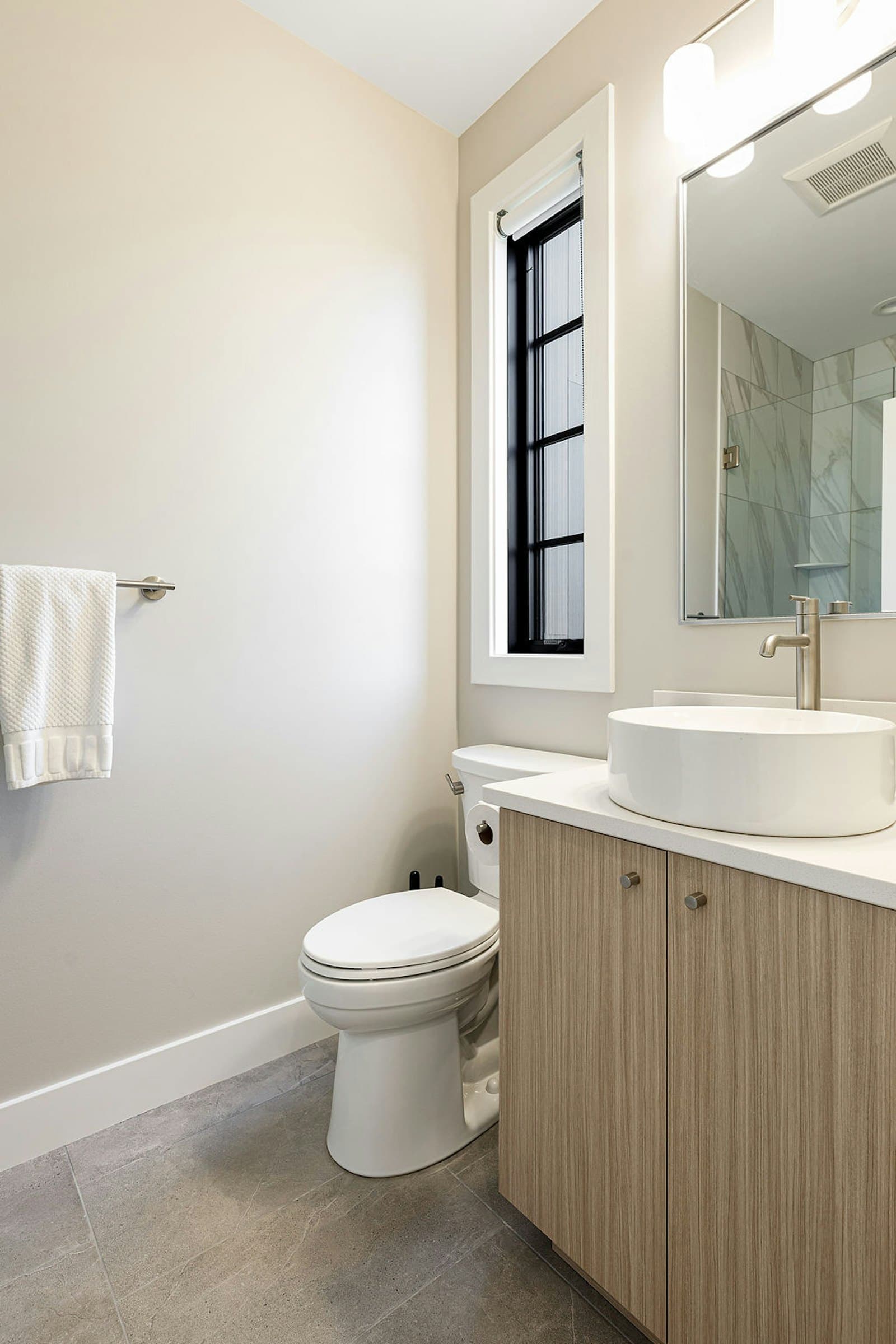 Bathroom vanity, toilet, and window