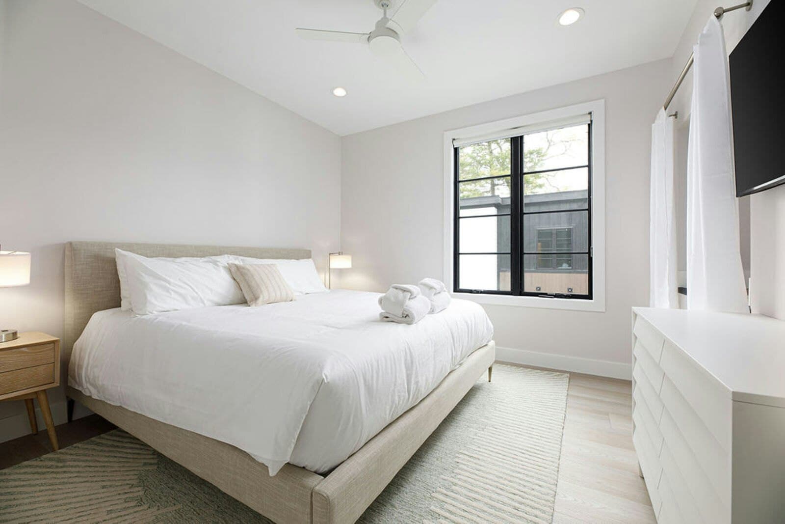 Bedroom with white linens, robes, and Smart TV